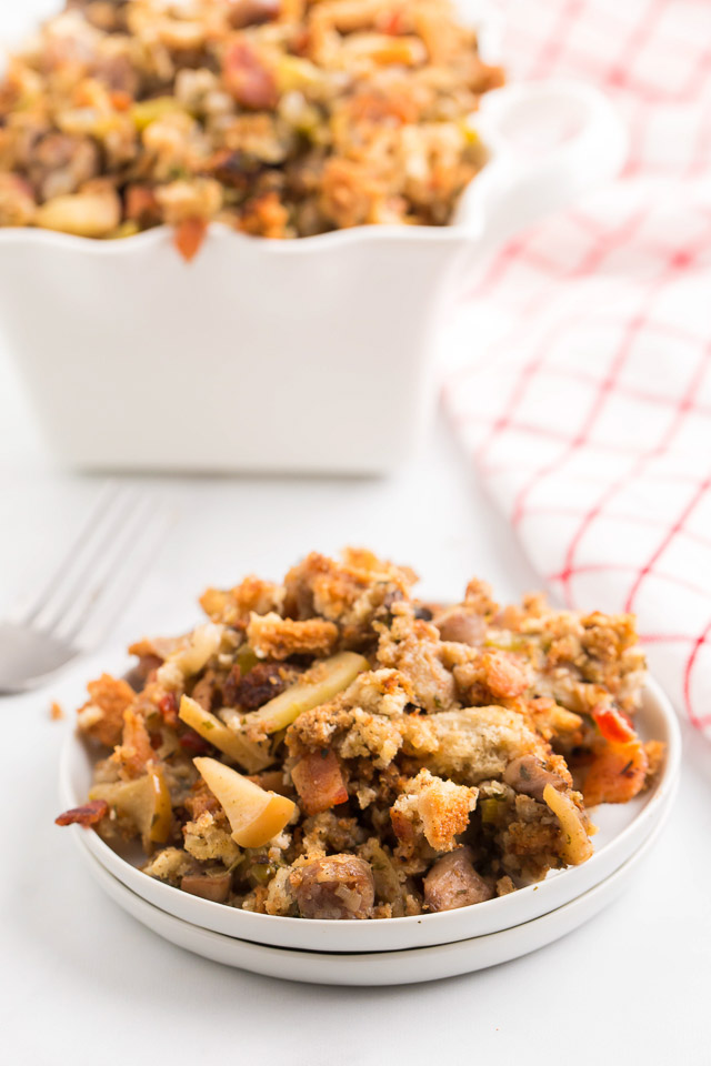 sausage dressing with apples and bacon on white plate and in serving bowl behind it