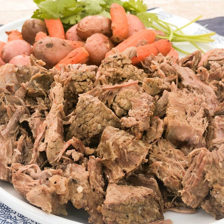 shredded pot roast on white platter with carrots and potatoes | 3 Packet Pot Roast Recipe