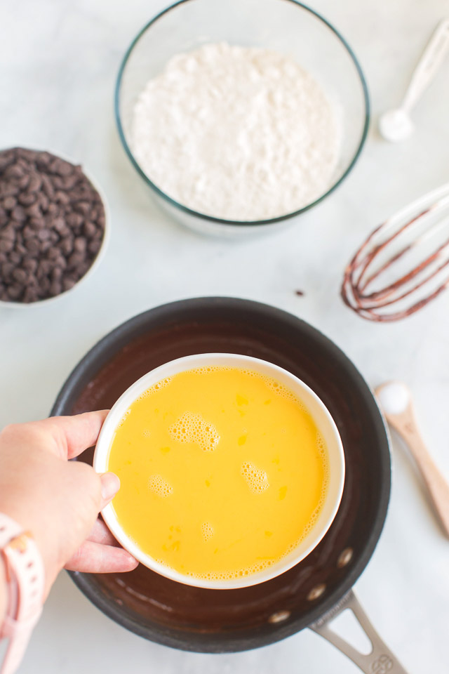 adding beaten eggs to melted dark chocolate in sauce pan