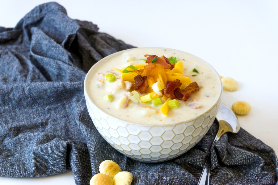 bowl of chowder with clams bacon, cheddar cheese and potatoes