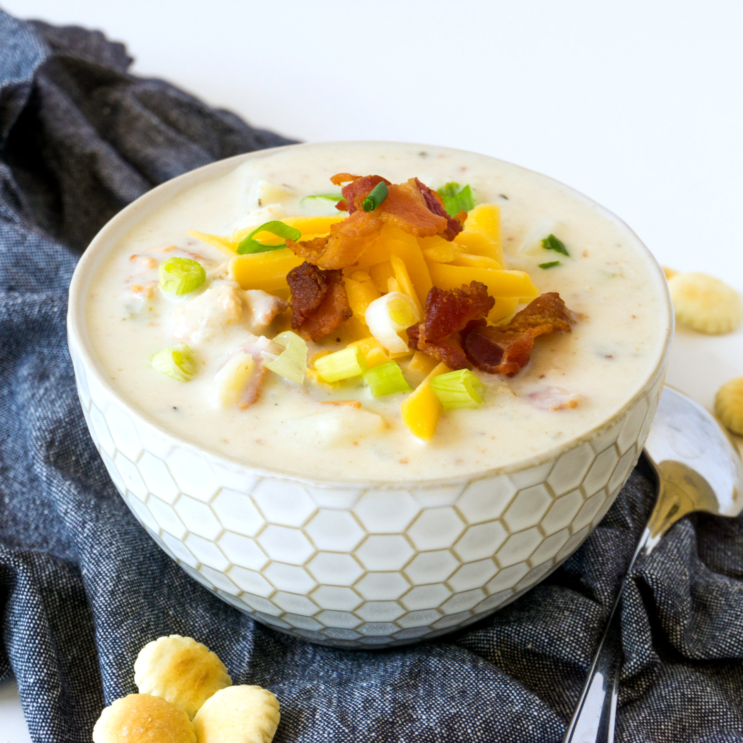 creamy New England clam chowder with bacon and cheese garnish in in white bowl