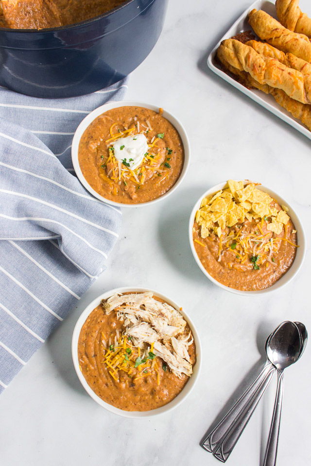 overhead photo: 3 bowls of creamy southwest chicken tortilla soup garnished with crushed tortilla chips and sour cream