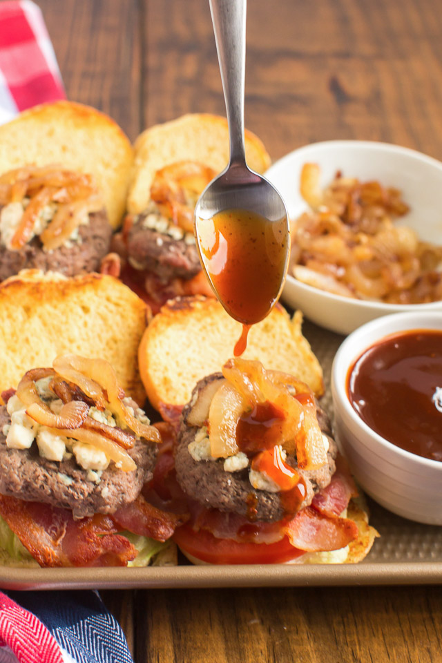 barbecue sauce dripping off a spoon onto a blue cheese slider