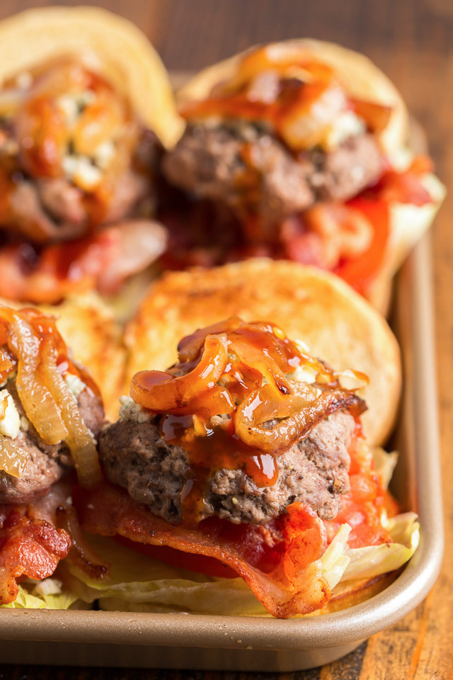 close up of mini bacon cheeseburgers on a metal serving tray