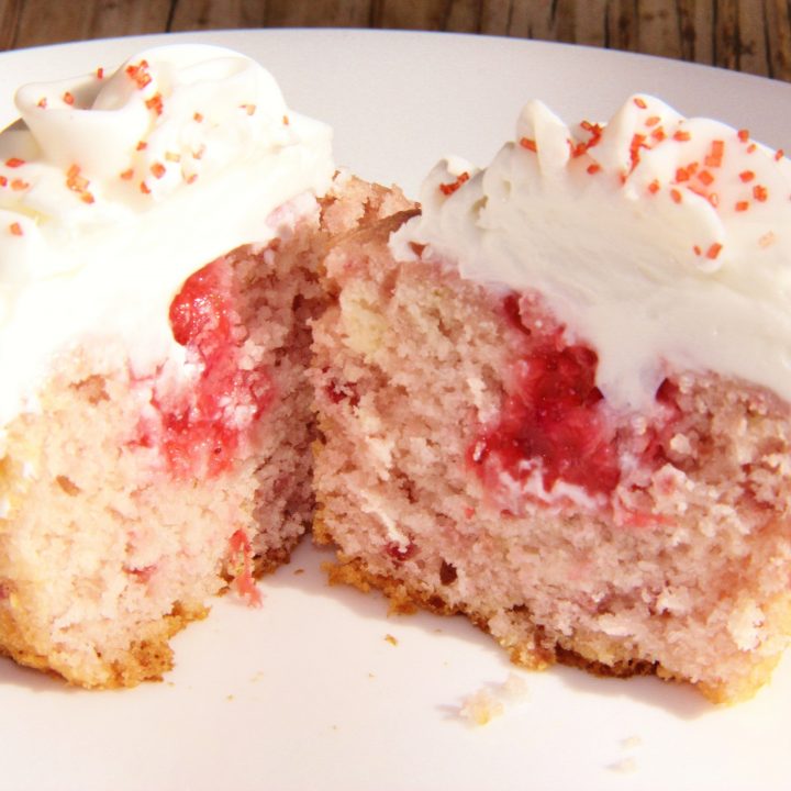 fresh strawberry cupcake topped with almond buttercream frosting, cut in half