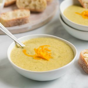 side view: spoon in white bowl of cheesy broccoli soup