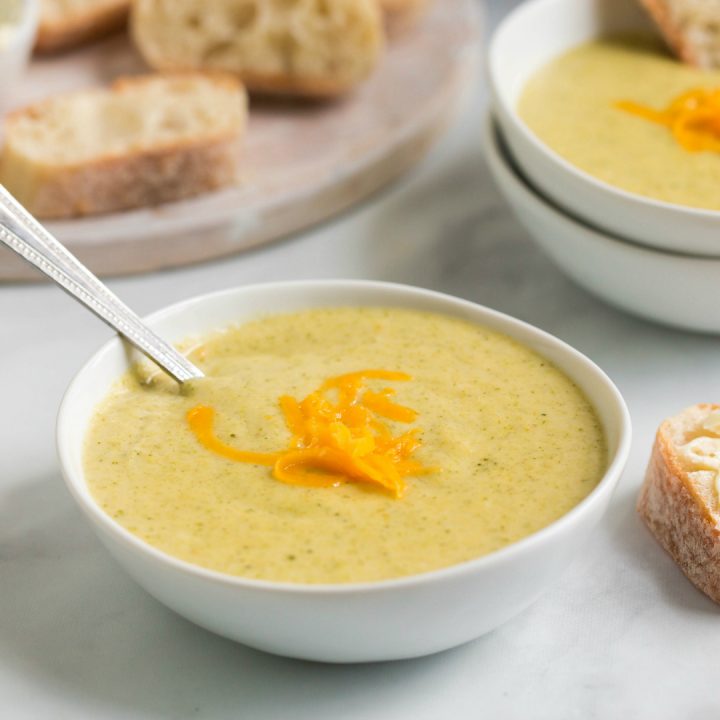 side view: spoon in white bowl of cheesy broccoli soup