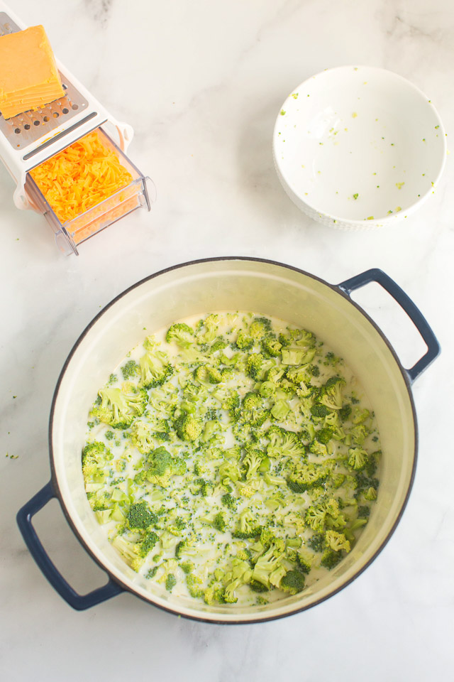 overhead photo: large soup pot with broth and fresh broccoli florets