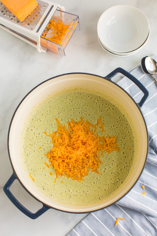 overhead photo: freshly shredded cheddar cheese melting into pot of soup