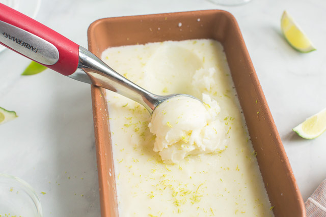 scooping homemade sherbet from a metal loaf pan