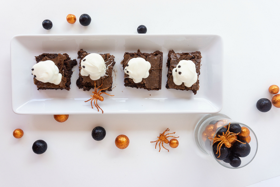 Brownies with ghost marshmallows on white platter