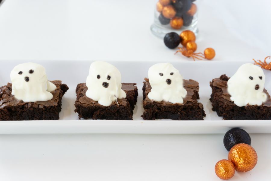 Brownies with ghost marshmallows on white platter