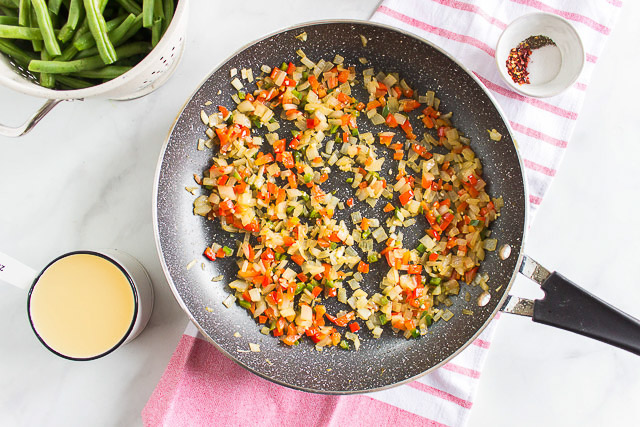 diced onion and bell peppers cooking in a skillet