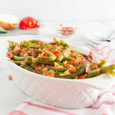 side view: spicy green beans and bacon in white serving dish