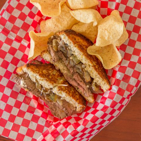 Flank Steak Sandwiches in a basket with potato chips