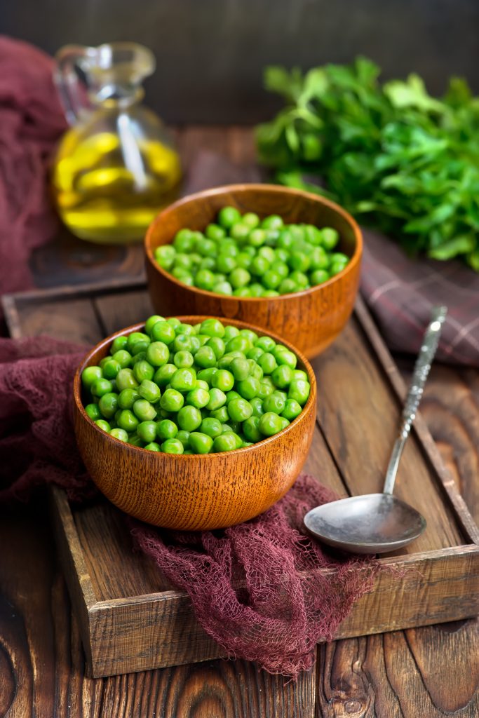 green peas in bowls and on a table