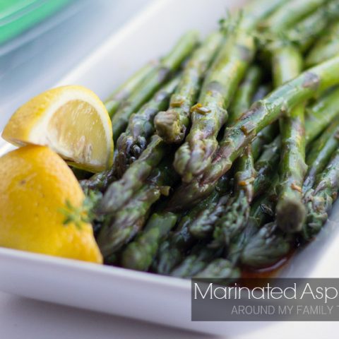 Marinated Asparagus on a platter with lemon wedges