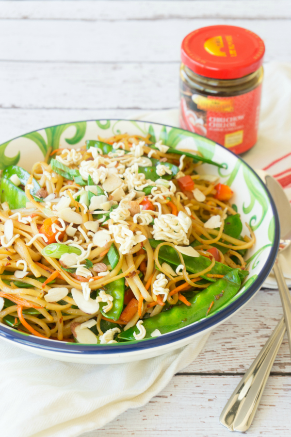 Change up your traditional summer pasta salad for this Spicy Asian Pasta Salad, it will be the hit of all your summer parties! This pasta salad is full of fresh vegetables and topped with some crushed ramen noodles and slivered almonds. #pastasalad
