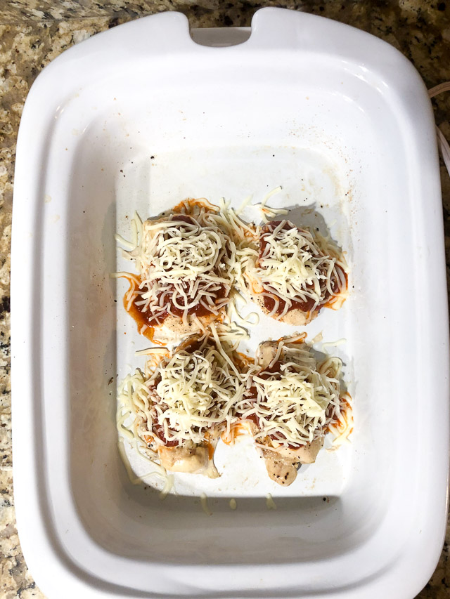 cooked chicken with pizza sauce and cheese in slow cooker