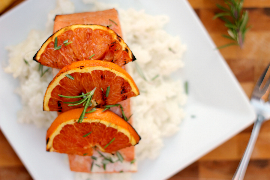 salmon on rice on a white plate with grilled oranges