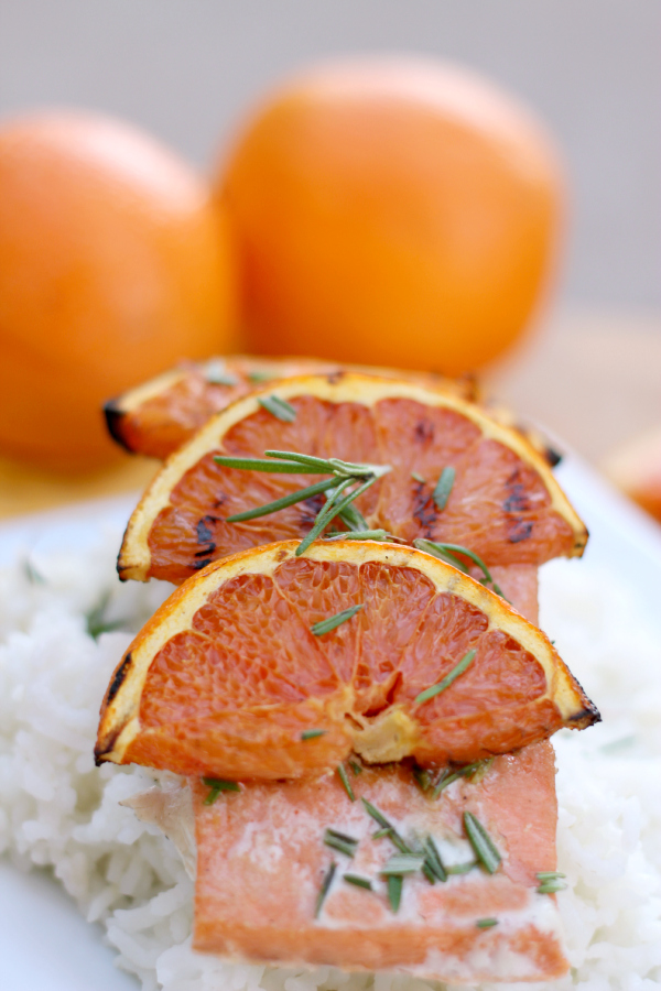 salmon on rice on a white plate with grilled oranges