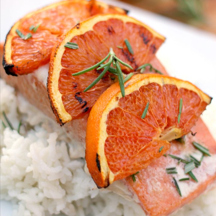 salmon on rice on a white plate with grilled oranges