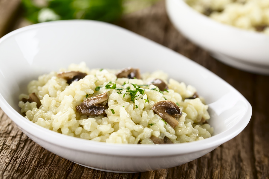 risotto in white bowl on wood table