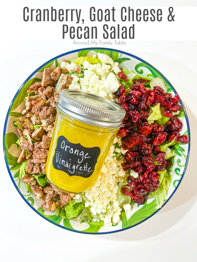 Cranberry, Goat Cheese, & Pecan Salad with Orange Vinaigrette in a bowl with a jar of dressing