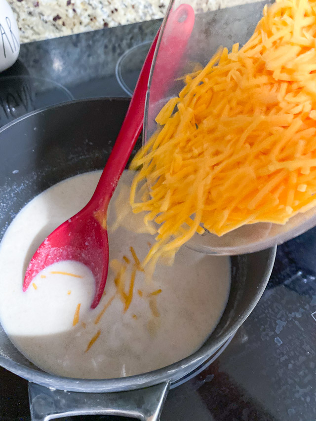 adding cheese to sauce