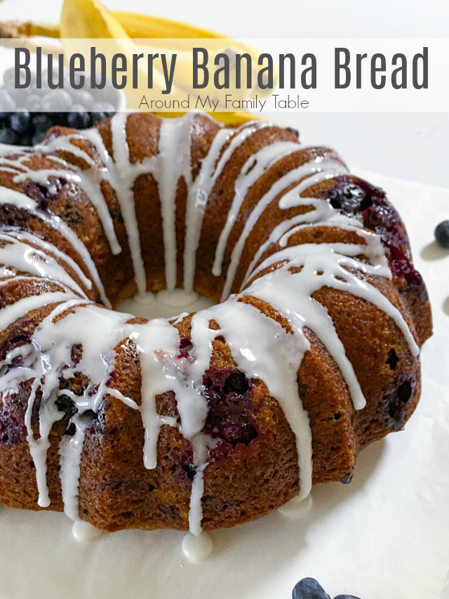 blueberry banana bread on white table with bananas and blueberries