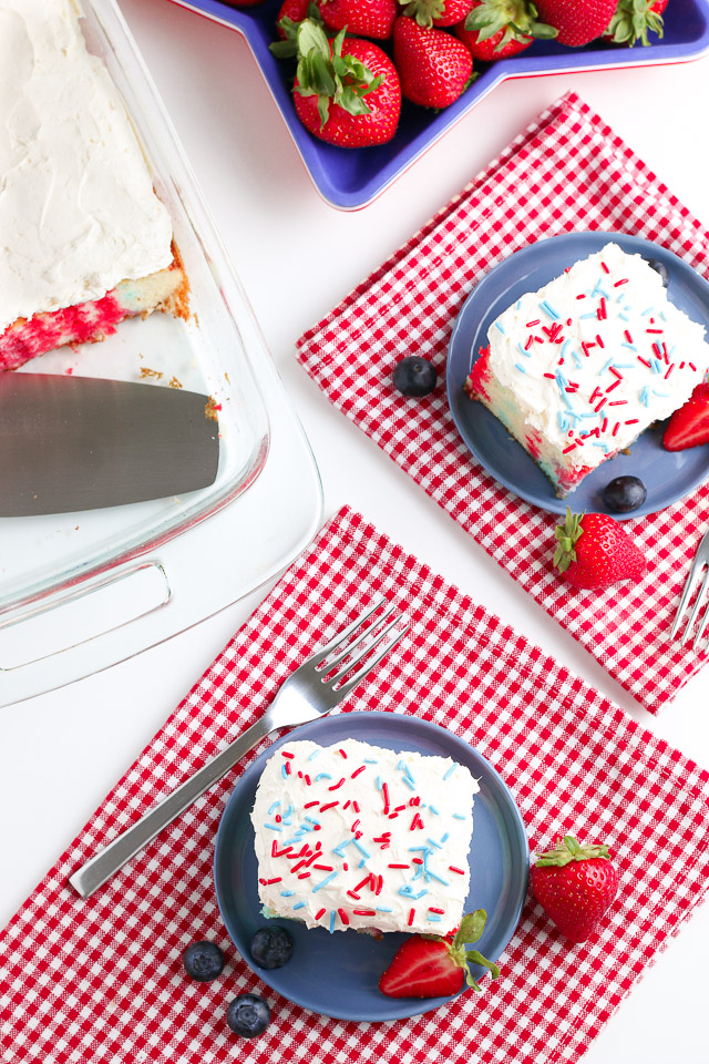 4th of July Poke Cake with berries on a white table with red checkered napkins