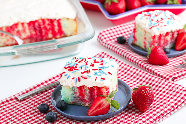 4th of July Poke Cake with berries on a white table with red checkered napkins