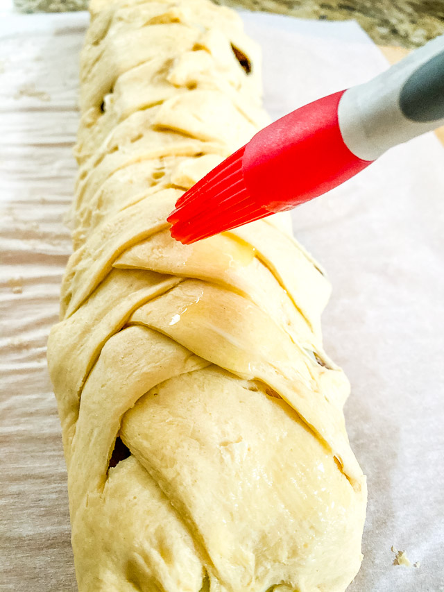 raw Steak & Provolone Crescent Braid being buttered