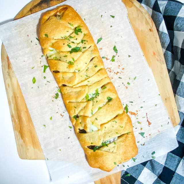 Steak & Provolone Crescent Braid on parchment paper on a pizza peel