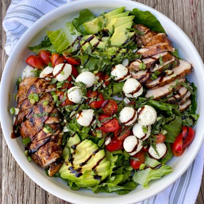 Italian Grilled Chicken Salad on a wood table with a white and blue towel