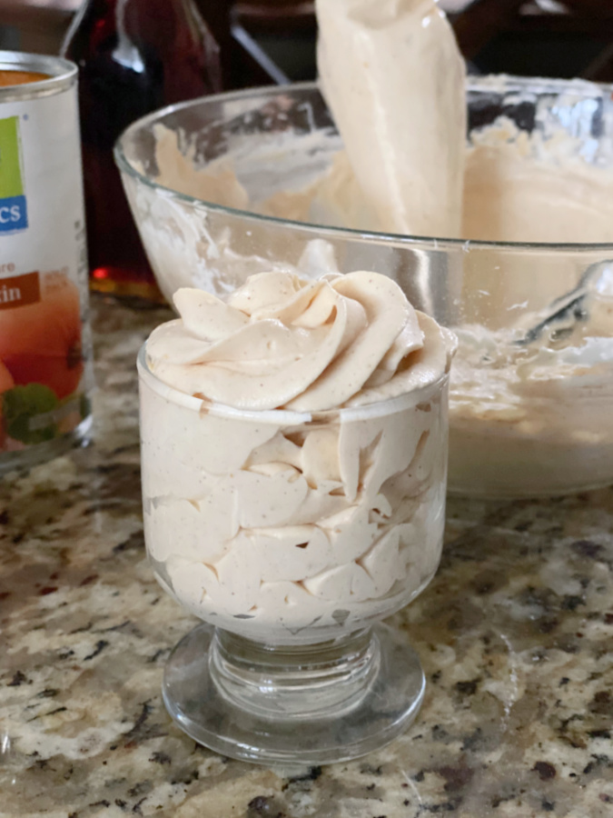 keto pumpkin mousse in a bowl being added to serving dish