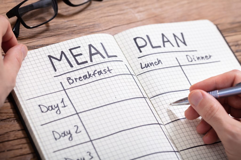 person writing a weekly menu planning