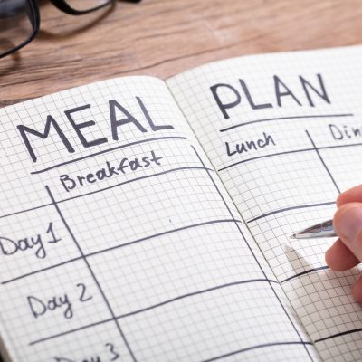 person writing a weekly menu planning