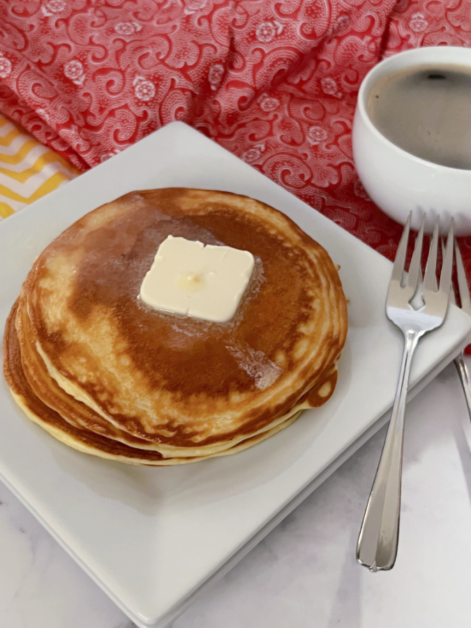 keto pancakes on white plate with a cup of coffee