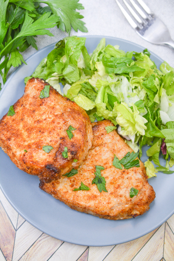 keto air fryer pork chops and salad on a blue plate